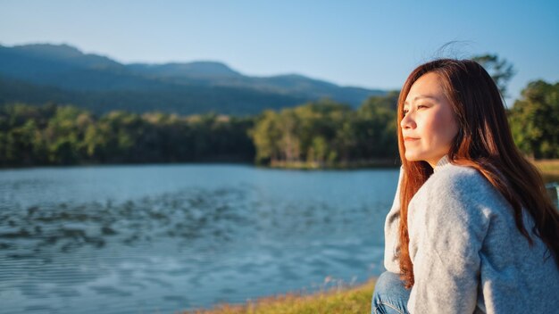 Foto bela mulher ao lado do lago contra as montanhas