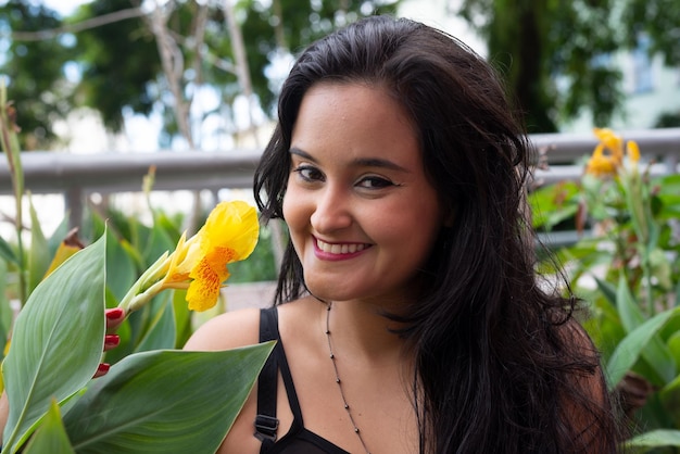 Bela mulher de cabelos pretos entre plantas verdes olhando para a câmera