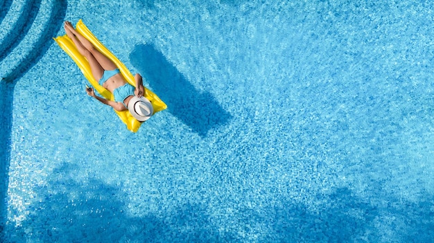 Foto bela mulher de chapéu na piscina vista aérea de drone de cima menina em biquíni relaxa