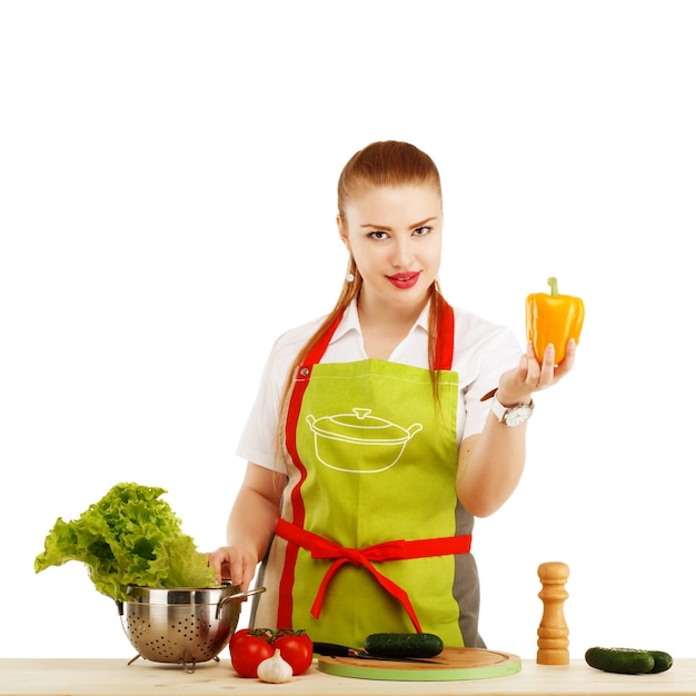 Bela mulher jovem sexy cozinhando uma refeição fresca contra branco.