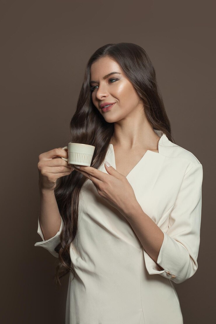 Bela mulher morena bebendo café em fundo castanho