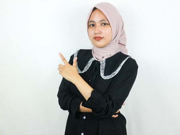 Bela mulher muçulmana asiática de hijab sorrindo apontando dedos para um lado conceito publicitário