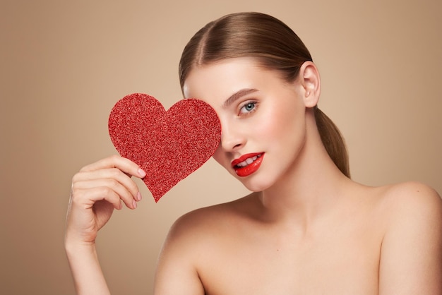 Foto bela mulher segurando um coração vermelho artificial