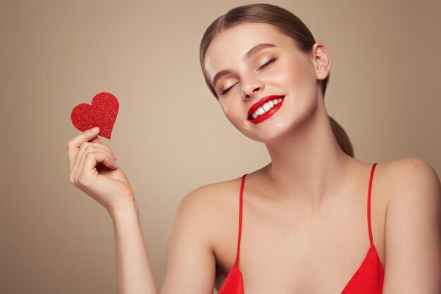 Foto bela mulher segurando um coração vermelho artificial