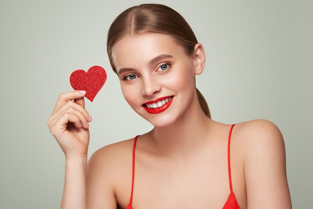 Bela mulher segurando um coração vermelho artificial