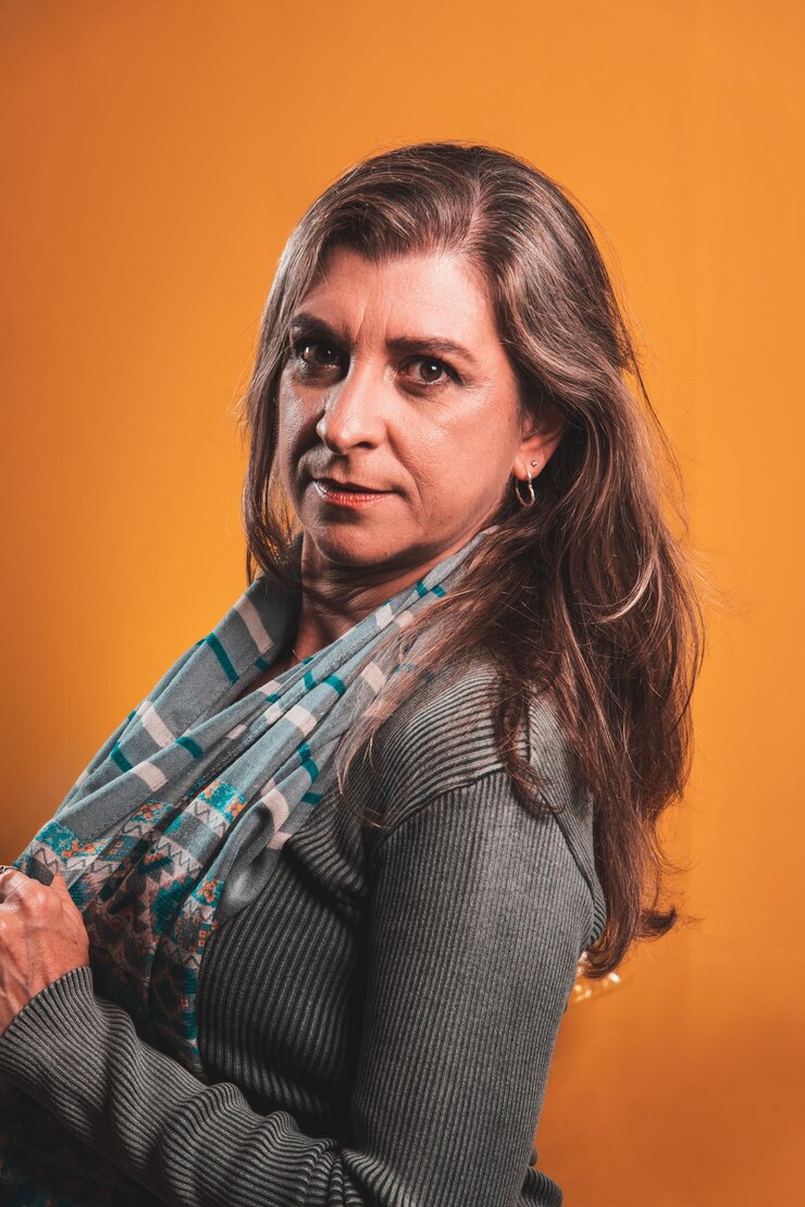 Foto bela mulher séria e calma com um lenço ao redor do pescoço isolada em fundo laranja