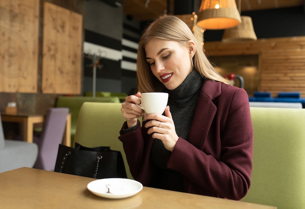 Bela mulher sorridente, bebendo café no café.