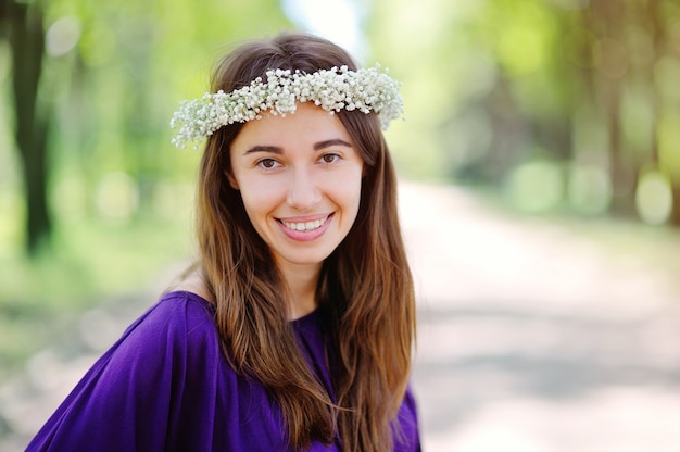 Bela mulher sorridente com uma coroa na cabeça no parque de verão