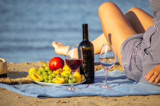 Bela mulher sorridente com uma taça de vinho na praia. Vinho tinto de frutas.