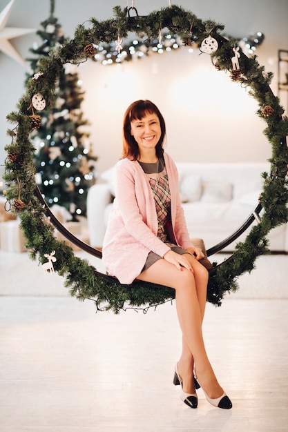 Bela mulher sorridente no banco de Natal. Árvore de Natal.