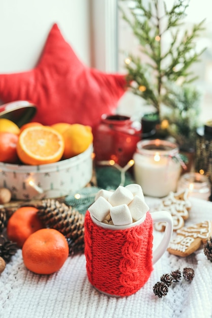 Bela natureza morta de Natal Uma xícara de chá quente com uma sexta manta de malha no peitoril da janela com decoração de Ano Novo