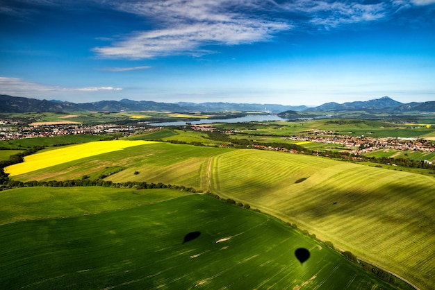 Bela paisagem campestre com campos verdes amarelos e lago ao fundo Liptov Eslováquia