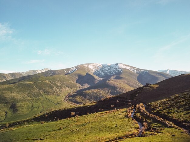 Bela paisagem campestre com prados e montanhas cobertas de montanhas verdes e nevadas em um dia ensolarado