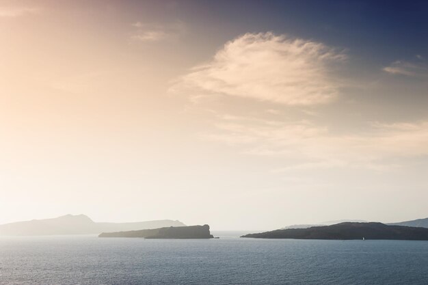 Bela paisagem com vista para o mar e ilhas ao pôr do sol. Ilha de Santorini, Grécia.