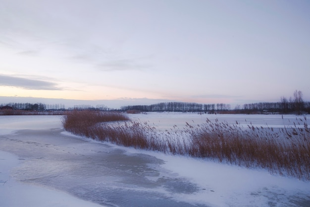 Bela paisagem de inverno ao pôr do sol com neblina e neve cobrindo terras agrícolas e o rio holanda
