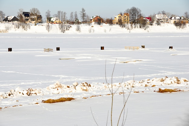 Foto bela paisagem de inverno - casas de campo, rio e árvores cobertas de neve branca