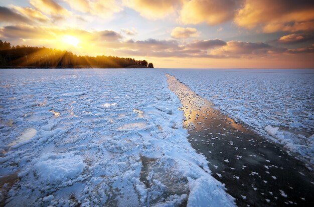 Bela paisagem de inverno com céu ao pôr do sol e lago congelado