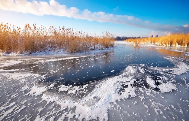 Bela paisagem de inverno com lago congelado, juncos e usina de energia.