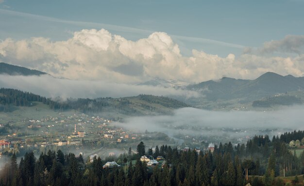 Bela paisagem de montanhas com neblina leve. Aldeia de montanha no nevoeiro no início da manhã. Vista das montanhas dos Cárpatos.