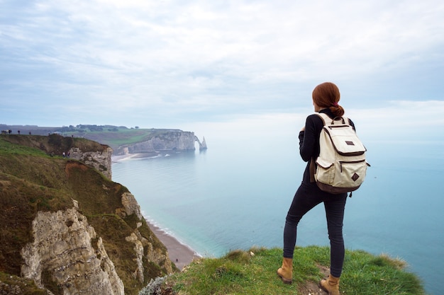 Bela paisagem, garota de pé à beira de uma rocha na etretat. frança