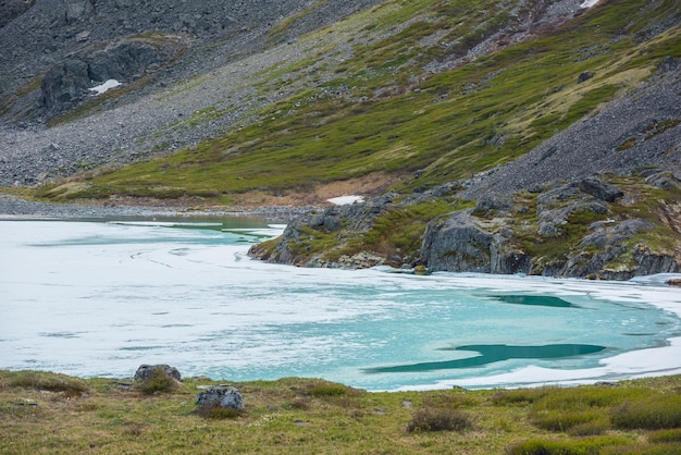 Bela paisagem montanhosa com água congelada no lago alpino entre rochas Fundo natural do lago gelado da montanha Textura alpina congelada Pano de fundo natural da superfície da água gelada Lago congelado fechado