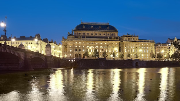 Bela Praga à noite. Teatro Nacional iluminado com reflexo no rio Vltava.