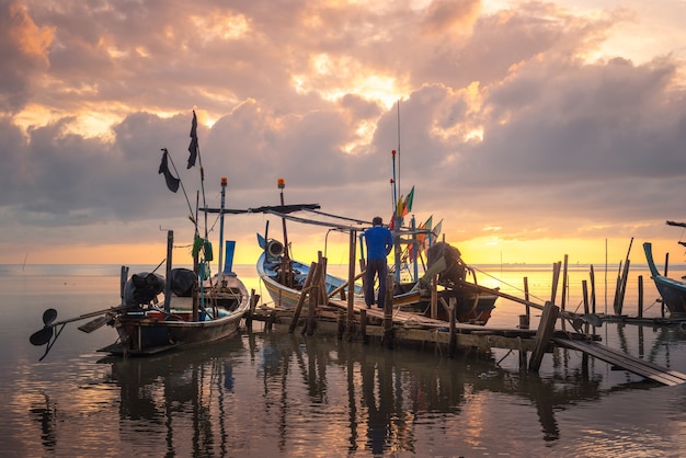 Bela praia com barco de pescador durante o nascer do sol na vila de pescadores