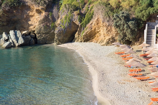 Bela praia de areia com água transparente e guarda-chuvas na grécia