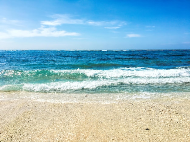 Bela praia de areia e ondas do mar azul suave