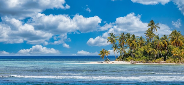 Bela praia tropical com areia branca, palmeiras, oceano turquesa contra o céu azul com nuvens