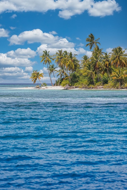 Bela praia tropical com areia branca, palmeiras, oceano turquesa contra o céu azul com nuvens