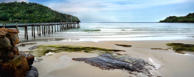 Bela praia tropical com velha ponte de madeira longa no