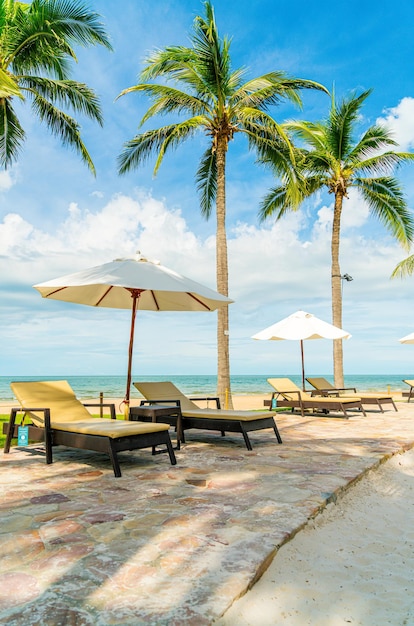 Bela praia tropical e mar com guarda-chuva e cadeira ao redor da piscina no hotel resort para viagens e férias