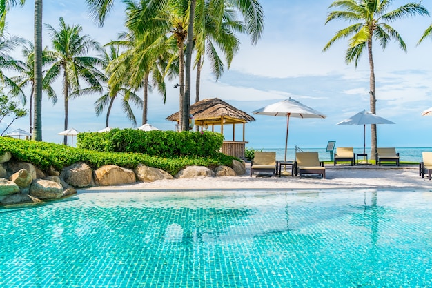 Bela praia tropical e mar com guarda-sol e cadeira ao redor da piscina em hotel resort para viagens e férias