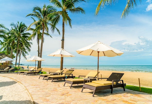 Bela praia tropical e mar com guarda-sol e cadeira ao redor da piscina em hotel resort para viagens e férias