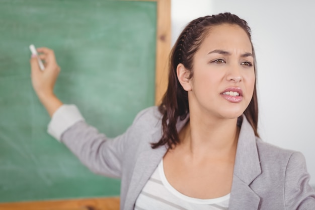 Bela professora escrevendo no quadro-negro em uma sala de aula