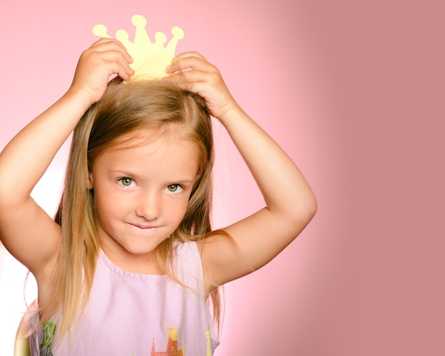 Bela rainha em coroa de ouro. menina princesa na coroa amarela e lindo vestido em fundo rosa.