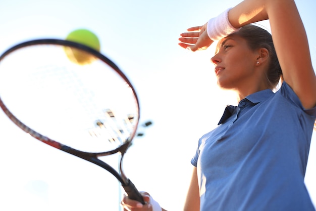 Foto bela tenista servindo a bola na quadra de tênis.
