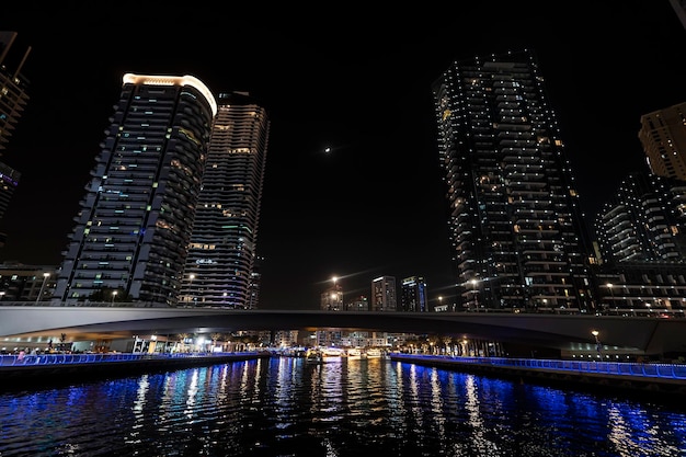 Bela visão noturna dos arranha-céus da marina de dubai do lado da água na ponte do rio em Dubai Marina iluminada à noite