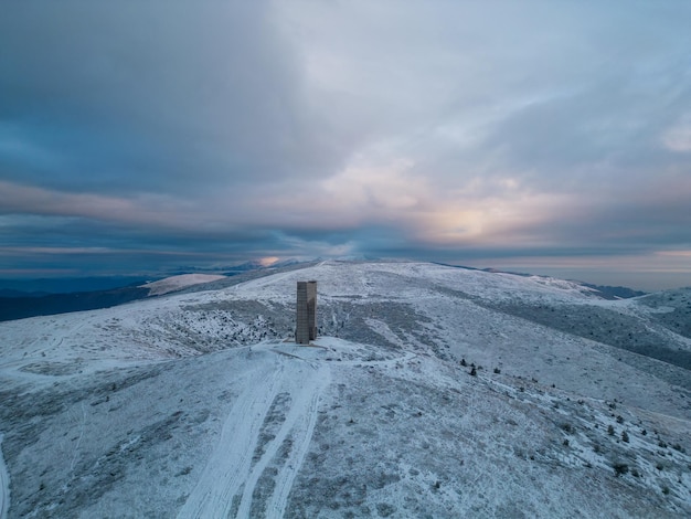 Bela vista aérea de montanhas cobertas de neve e o Monumento Arco da Liberdade no cume principal das montanhas dos Balcãs Bulgária na manhã de inverno