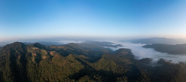 Bela vista aérea de paisagem incrível Névoa de montanha no vale de manhã com fundo de céu azul