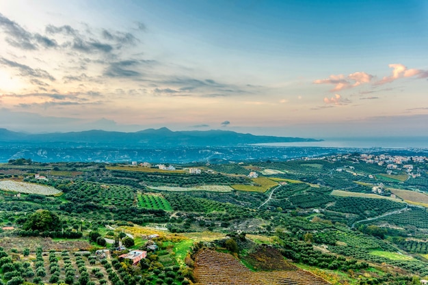 Bela vista da paisagem com oliveiras e montanhas na ilha de Creta durante o pôr do sol