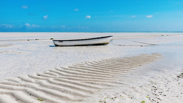 Bela vista da praia de Zanzibar na maré baixa. Barco na praia.