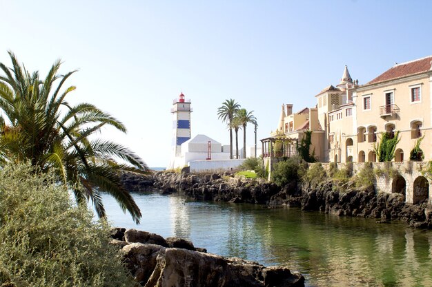 Bela vista da praia, farol e vila no dia ensolarado. cascais. portugal.