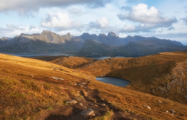 Bela vista das colinas de chocolate, lagos, mar e montanhas ao pôr do sol nas ilhas lofoten na Noruega polar no outono