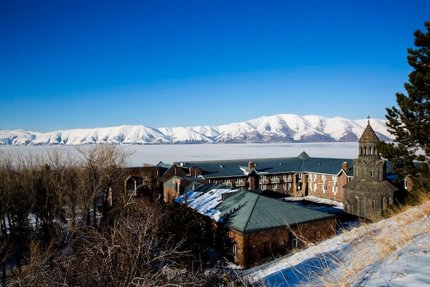 Bela vista das montanhas cobertas de neve com o Lago Sevan coberto de gelo e uma igreja cristã