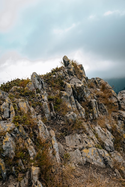 Foto bela vista das montanhas rochosas verdes brilhando sob o céu nublado