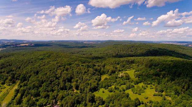 Bela vista de uma colina com uma floresta verde e céu azul com nuvens brancas. vista aérea.