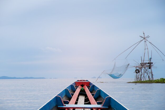 Bela vista do barco de madeira cênica no lago com grande levantamento de rede dos aldeões nas províncias de phatthalung, tailândia.