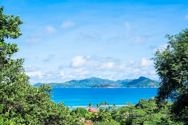 Bela vista do mar com montanhas distantes emolduradas por folhagem tropical verde